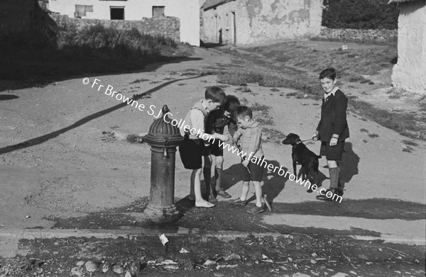 CHILDREN PLAYING IN STREET AROUND WATER PUMP